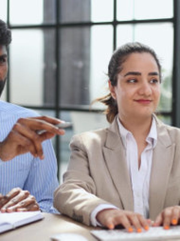 225215315-young-indian-mentor-coach-talking-with-female-colleague-teaching-trainee-having-business